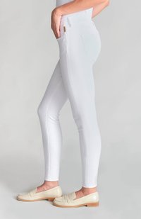 Pantalones blancos ajustados con una tela texturizada, con bolsillos laterales y una cintura alta, combinados con mocasines de color beige claro.