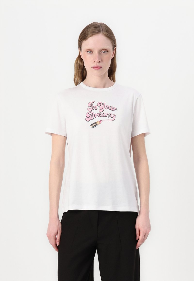 Tricou alb din bumbac cu text pastel roz "În visele tale" și un grafic ilustrativ cu un ruj pe față. Mâneci scurte, gât rotund.