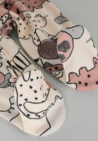 Des pyjamas en coton doux, avec un motif animal rose et crème, bordé de contours foncés. Comprend une fermeture éclair et des semelles texturées.