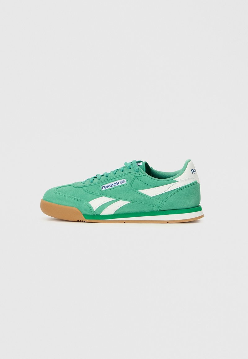 Baskets basses Reebok vertes avec des bandes blanches et une semelle gomme, montrées de profil droit sur fond uni.