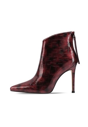 Stivaletto in pelle patinata bordeaux con punta affusolata, texture coccodrillo e tacco alto e sottile. Dotato di zip sul retro per la chiusura.