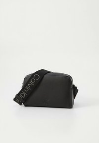 Czarna skórzana torba na ramię o prostokątnym kształcie, wyposażona w pasek z kontrastowym logo i zapięcie na zamek. Fakturowana powierzchnia z minimalnymi detalami.