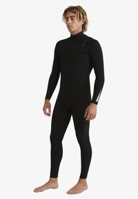Full-body wetsuit in black neoprene, features long sleeves, close-fit design, and a zip pocket on the chest for convenience.