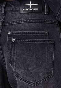 Jeans in denim scuro con due tasche posteriori, accenti di hardware argentato e un'etichetta in pelle nera con il logo "PXP" sulla vita.