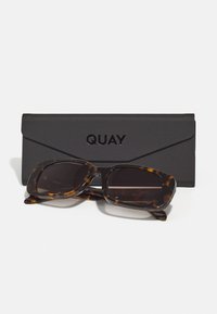 Ochelari de soare cu rame dreptunghiulare din material tartan, cu lentile întunecate și un finisaj lucios, însoțiți de un toc protector negru cu logo-ul "QUAY".