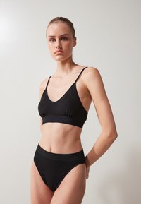 Set de sutien negru și chiloți cu talie înaltă, realizat dintr-un material moale, cu bretele subțiri, design cu gât în formă de V și o talie netedă.
