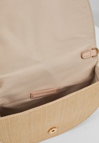 Beżowa torebka z tkaniny plecionej z beżowym wnętrzem, zapięcie na magnes i metka "Forever New" wewnątrz.