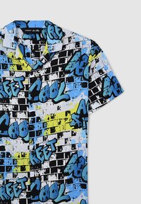 Camicia a maniche corte con un design di graffiti multicolore, dettagliata in blu, nero e giallo su uno sfondo bianco, realizzata in tessuto leggero.