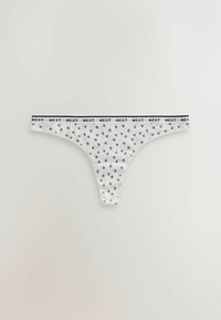 Culotte string blanche à pois violets avec une ceinture blanche répétant le mot "NEXT" en lettres noires.