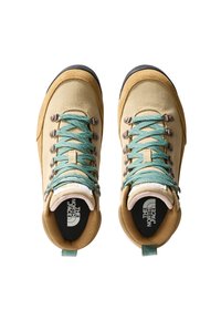 Beige Wanderschuhe mit strukturiertem Obermaterial, türkisen Schnürsenkeln und silbernen Ösen. Merkmale eine schwarze gepolsterte Innensohle und ein Logo an der Ferse.
