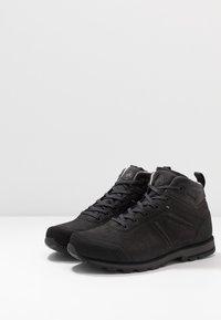 Schwarze High-Top-Schuhe aus Wildleder und synthetischen Materialien, mit einer strukturierten Oberseite, runden Schnürsenkeln und einer robusten Sohle mit Grip-Mustern.