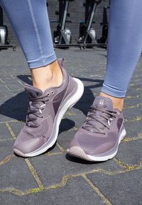 Purple athletic shoes with a mesh upper, patterned accents, and a white sole. Fitted with laces and a pull tab at the heel.