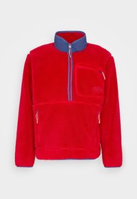 Polo de forro polar rojo con cuello azul y bolsillo en el pecho con cremallera. Tiene dos bolsillos laterales con cremallera y tejido texturizado. Diseño de cremallera de un cuarto.