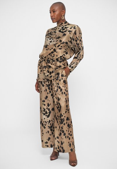 Leopard print, satin outfit featuring a long-sleeve top with high neck and drawstring waist, paired with wide-leg trousers. Tan and black colors.