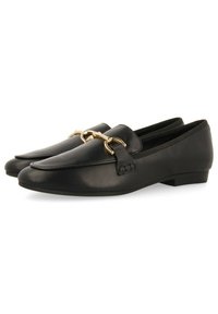 Mocassins en cuir noir avec un accent en chaîne dorée, texture lisse, bout rond et faible talon pour un porté multifonction.