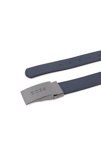 Σκούρα μπλε δερμάτινη ζώνη με ματ μεταλλική αγκράφα χαραγμένη με το "BOSS." Διαθέτει ομαλή υφή και πολλαπλές τρύπες ρύθμισης κατά μήκος του ιμάντα.