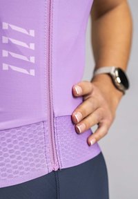 Purple athletic top with a front zipper, textured lower section, and white graphic accents. Features a close-fitting design for active wear.