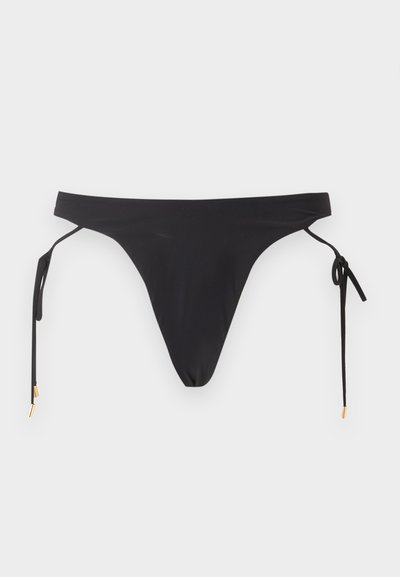 Μαύρο κάτω μέρος μπικίνι με δέσιμο στα πλάγια και χρυσά τελειώματα σε απλό ανοιχτό φόντο.