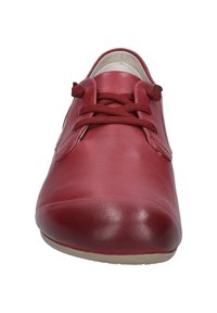 Scarpa in pelle rossa con punta arrotondata, dettagli cuciti e lacci marroni. Texture liscia e design minimalista con suola a profilo basso.