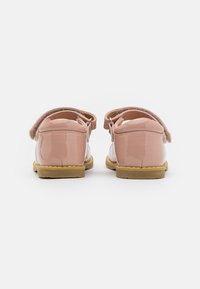 Zapatos de charol rosa con punta redondeada, parte trasera de tejido suave y correa ajustable. Suela de goma beige destacada para mayor comodidad y durabilidad.