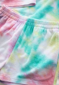 Shorts colorés tie-dye en tissu éponge doux, avec des nuances pastel de rose, vert et jaune, dotés d'une ceinture élastique.