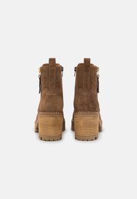 Ruske nubuk ankle sa štiklom od drva, zatvaranje na zatvarač i kontrastni detalj šivanja. Flat gumeni đon za stabilnost.