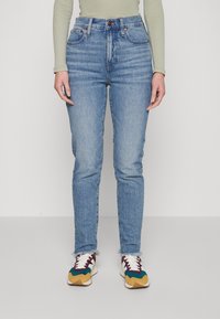 Světle modré džíny s vysokým pasem, slim fit, s klasickým pětipocket designem a třásněmi na kotnících, doplněné multikolorovými teniskami.