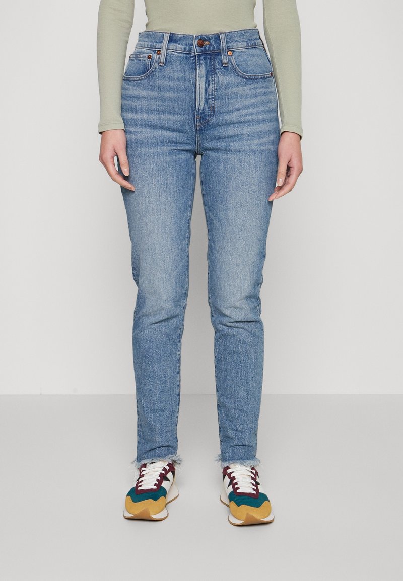 Světle modré džíny s vysokým pasem, slim fit, s klasickým pětipocket designem a třásněmi na kotnících, doplněné multikolorovými teniskami.