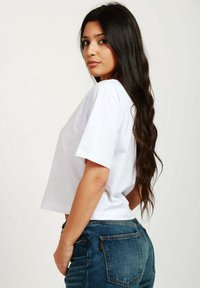 T-shirt bianco a maniche corte in cotone, con una vestibilità comoda. Abbinato a jeans in denim blu a vita alta.