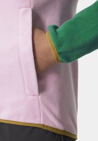 Fleece bunda s růžovým tělem, zelenými rukávy a zlatým lemem. Disponuje boční kapsou a strukturovanou tkaninou pro teplo.