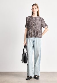 Μπλούζα κοντομάνικη με λεοπάρ σχέδιο και φούστα peplum, συνδυασμένη με ανοιχτό μπλε παντελόνι με φαρδιά πόδια. Η εμφάνιση ολοκληρώνεται με μια μαύρη τσάντα και μαύρες μπαλαρίνες.