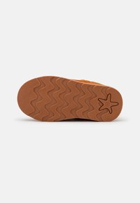 Suela de goma marrón con un patrón ondulado. Superficie texturizada con un acento en forma de estrella y número en relieve. Diseño duradero apto para varios terrenos.