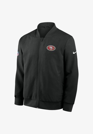 Veste noire zippée en tissu lisse avec un logo des San Francisco 49ers sur la poitrine gauche et un Swoosh Nike sur la manche droite.