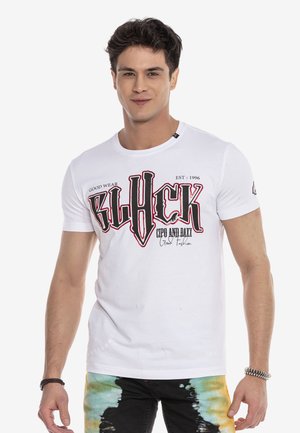 White cotton t-shirt with a round neck, featuring bold black and red graphic text on the front. Short sleeves, paired with colorful tie-dye pants.