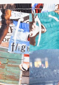 Pantaloni corti multicolore con motivi vari, tra cui animali e testi. Realizzati in tessuto leggero con elastico in vita e cordoncino.