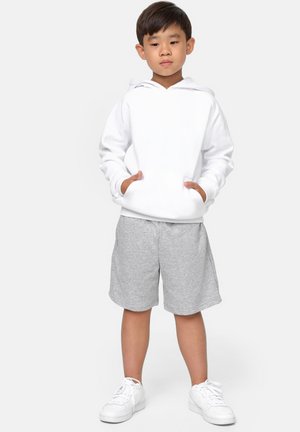 Hvit hettegenser med frontlomme, kombinert med grå shorts. Hvite joggesko fullfører antrekket. Enkelt design, myke teksturer, avslappet stil.