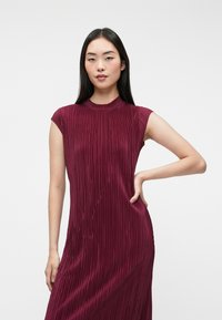 Βουργουνδί ριχτό φόρεμα με ψηλή λαιμόκοψη και κοντά μανίκια, με κάθετες γραμμές, λεία υφή και ρέουσα σιλουέτα.