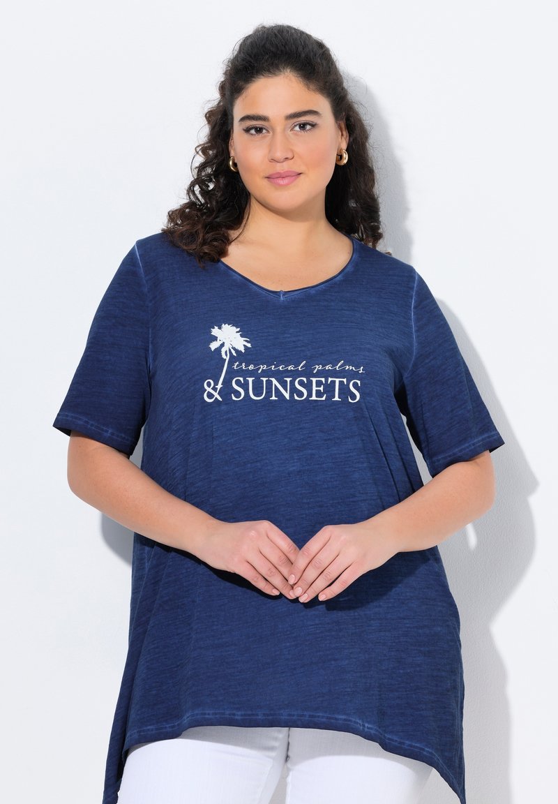 Tunik dengan lengan pendek berwarna biru laut, memiliki leher bulat dan hem melengkung. Dilengkapi dengan teks putih dan grafik pohon palem. Tekstur kain ringan.