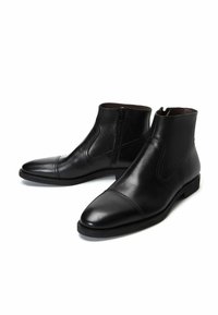 Botas negras de cuero hasta el tobillo con un acabado liso, puntera puntiaguda y cremallera lateral. Incluyen una suela plana y detalles de costura mínimos.