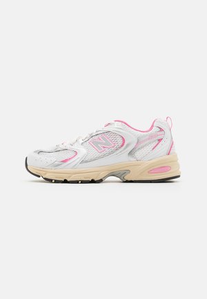 Baskets blanches et roses avec des panneaux en mesh, semelle beige et logo sur le côté, conçues pour la course ou un usage décontracté.