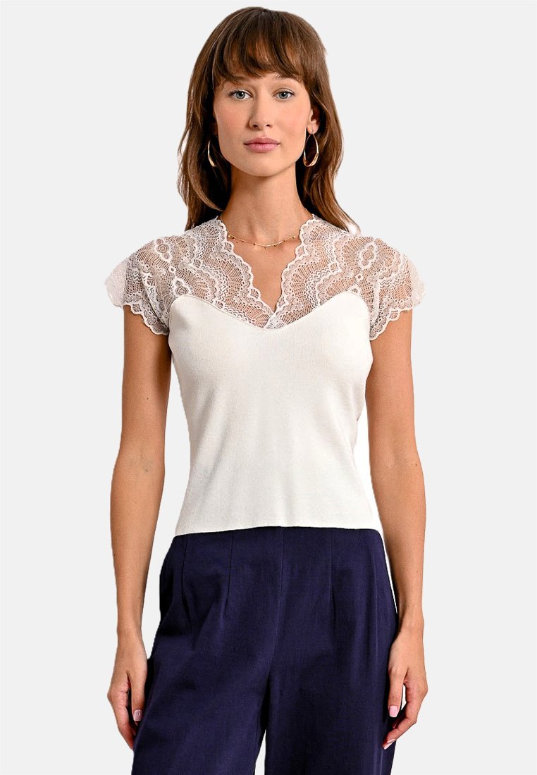 Top bianco con maniche corte in pizzo, scollatura a V, corpetto aderente e texture liscia, abbinato a pantaloni a palazzo blu navy.