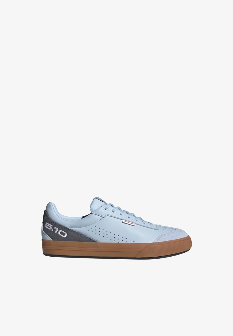 Zapatilla deportiva azul claro de corte bajo con suela de goma marrón, parche gris en el talón, logo blanco "5.10", lateral perforado y cierre de cordones.