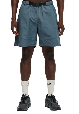 Blå atletiske shorts med elastisk talje og bælte, har sidelommer og et let, struktureret stof. Bæres med sorte sneakers og hvide sokker.