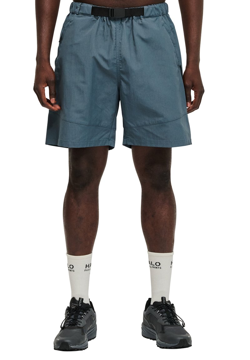 Blauwe sportshorts met een elastische tailleband en riem, met zijzakken en een lichte, gestructureerde stof. Draagt met zwarte sneakers en witte sokken.