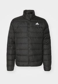 Crna puffer jakna s visokim ovratnikom, zatvaranjem na zip i kvadratnim dezenom. Sadrži bijeli Adidas logo na lijevoj strani prsnog koša. Glatka, sjajna tkanina.