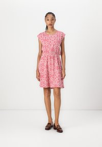 Pink patterned dress with cap sleeves, cinched waist, and diamond designs, complemented by brown loafers with hardware accents.
