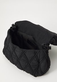 Black quilted fabric bag with a soft, textured surface; features a drawstring closure and a zippered inner pocket.