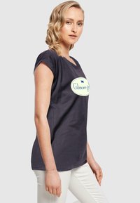 Námořnické tričko s kulatým výstřihem a ohrnutými krátkými rukávy; obsahuje světlebarevné oválné logo s nápisem "Gilmore girls".