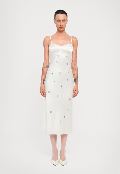 Weißes Satin-Kleid mit dünnen Trägern, figurbetontem Oberteil und fließendem Rock. Verziert mit blauen und silbernen bestickten Sternmotiven.