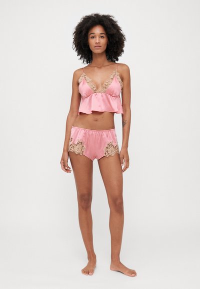 Set di pigiami in satin rosa, composto da una maglietta corta con bordo in pizzo e pantaloncini abbinati, decorati con dettagli in pizzo all'orlo. Tessuto morbido, vestibilità rilassata.